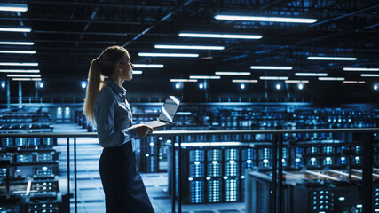 Fototapete - Data Center Female IT Specialist Uses Laptop Computer. Information Technology Engineer Overseeing and Walking Through Cloud Computing Server Farm Maintenance and Monitoring.