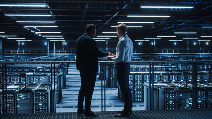 Poster - Data Center IT Specialist and e-Business Enrepreneur Talk, Use Laptop. Two Information Technology Professionals Walking on Bridge Overlooking Cloud Computing Server Farm.