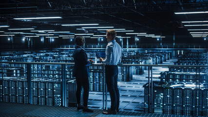 Poster - Data Center Male IT Specialist and Female e-Business Enrepreneur Talk, Use Laptop. Two Information Technology Professionals on Bridge Overlooking Big Cloud Computing Server Farm.