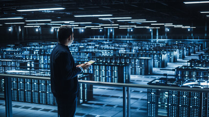 Poster - Handsome Smiling IT Specialist Using Tablet Computer in Data Center. Succesful Businessman and e-Business Entrepreneur Overlooking Server Farm Cloud Computing Facility.