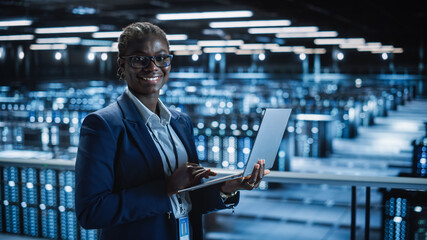 Leinwandbilder - Data Center: Female Programmer Using Laptop Computer, Smiling and Looking at Camera. In Cloud Computing Server Farm System Administrator Working on IT Maintenance for Iaas, saas, paas.