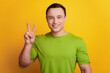 © Tetiana - Portrait of friendly positive man show v-sign gesture on yellow background