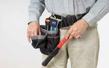 Builder's hand grabs hammer, and other takes nail from bag on waist to do work, close-up on light background