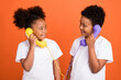 © deagreez - Photo of small funky girl boy talk telephone wear white t-shirt isolated on orange background