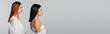 © LIGHTFIELD STUDIOS - side view of brunette asian woman and redhead model posing isolated on grey, banner