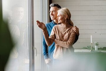 Happy mid aged white couple standing in modern living