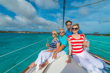 Wall Mural - Senior and young couples, family, enjoying sailing trip on a luxury summer holiday vacation, sunset and ocean in background, love and romance on a beautiful yacht