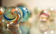Glass marbles handmade antique with colourful swirl patterns on a reflective glass surface
