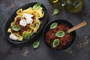 Poster - Top view of pappardelle with bolognese sauce and mozzarella cheese over brown stone background, horizontal shot