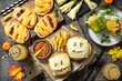 © elena_hramowa - Halloween party food corner table scene over a wood background. Halloween party burger, mummies mini pizzas, halloween drink, Bell peppers with spaghetti and and minced tomato turkey.