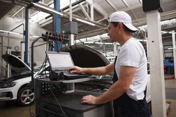 Wall Mural - Experienced car mechanic doing computer car diagnostics at the workshop