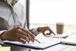 © kamiphotos - Businesswoman's hand holding a pen pointing at a bar chart on a corporate financial information sheet, the businesswoman examines the financial information provided by the finance department.