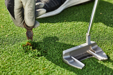 golfer properly repair a divot mark on putting green using divot tool. ball mark repair tool or divo