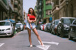 Fashion model posing outside in jeans shorts and red top.