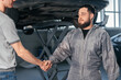 Mechanic shaking hands with car owner in the workshop garage. Car auto services concept