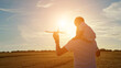 © lenblr - Young father carries toddler son on shoulders and toy red plane in hand and turns round flying airplane in yellow field at sunset light, sunlight