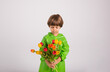 © Яна Айбазова - portrait of a little boy in a green raincoat holding a bouquet of colorful tulips on a white background with a place for text