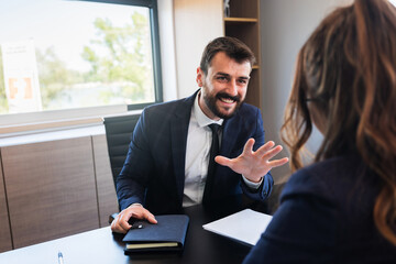 Friendly informal conversation between male and female coworkers in modern office.