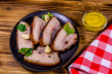 Wall Mural - Slices of baked pork belly, garlic and parsley on a black plate