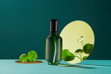 Blank bottle for mockup. Cosmetics product with centella asiatica (gotu kola) extract in dark green background and centella asiaticaa reflection in the mirror. 