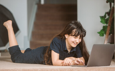 portrait of adorable child girl doing on-line learning using laptop at home, home schooling, online education