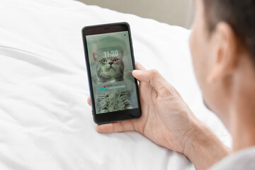 Sticker - Young man with mobile phone checking his e-mail in bedroom