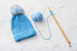 Warm knitted hat, yarn and needles on light background