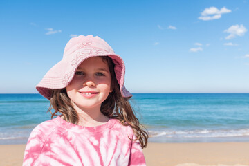 Portrait of smiling girl at beach in pink hat (selective focus)