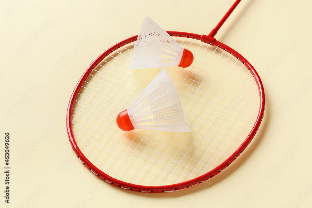 Badminton racket and shuttlecocks on color background