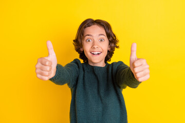 Poster - Portrait of attractive cheerful boy giving you two thumbup great solution isolated over bright yellow color background