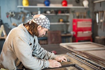 Wall Mural - Male carpenter working on old wood in a retro vintage workshop.