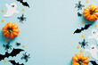 Halloween flat lay composition with orange pumpkins, ghosts, spiders, bats on blue background. Happy Halloween holiday greeting card mockup. Flat lay, top view, copy space.
