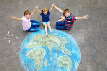 Little Preschool Girl And Two School Kids Boys With Earth Globe Painting With Colorful Chalks On Ground. Happy Earth Day Concept. Creation Of Children For Saving World, Environment And Ecology.