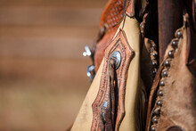 Cowboy Chaps Hanging On A Fence With Focus On Decorative Detail And Copy Space