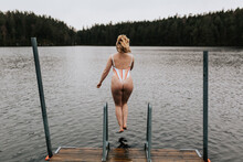 Rear View Of Woman Jumping Into Lake