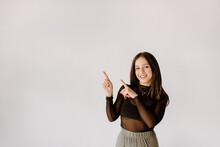 Smiling Young Woman Pointing Towards Wall