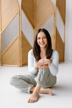 Studio Shot Of Young Woman Sitting On Floor