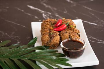 A serving of tauhu bergedil, a famous Malaysian dish with spicy soy sauce as dips. Blurred background