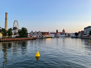 Canvas Print - Beautiful view of river between buildings and houses with blue sky on the horizon in Gdansk, Poland