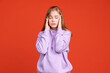 © Lustre Art Group  - Cropped portrait of young tired girl touching her head isolated on red studio background. Concept of human emotions
