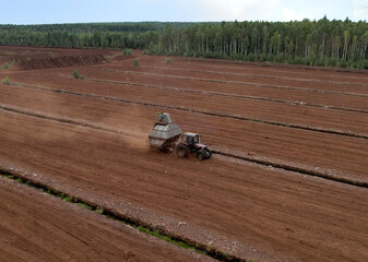 Peat Harvester Tractor on Collecting Extracting Peat. Mining and harvesting peatland. Area drained of the mire are used for peat extraction. Drainage and destruction of peat bogs.