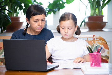 Study online with video call teacher. Young girl and her mother learn online at home.Social distancing.