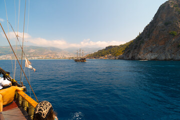 Wall Mural - Old pirate ship on the water of Mediteranean sea. Tourist entertainment, coastal tour. Summer sunny day. Mountain shore of Alanya. Turkey.