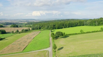 Sticker - Up moving drone shot of a beautiful summer landscape with hills, meadows and aforest. Agricultural terrain and countryside in Lower Saxony, Germany.