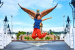 Happy girl tourist posing next to sculpture of a red eagle spreading its wings. Popular tourist spot on Langkawi island