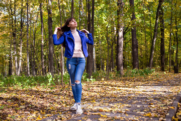 young beautiful womanin autumn park in sun shines on yellow trees background