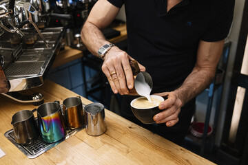 Sticker - Closeup shot of bartender's hands preparing a tasty cappuccino by pouring whipped milk in the coffee