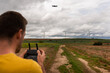 © Oier - Back View Of An Unrecognizable Caucasian Young Adult Flying A Drone In A Sustainable Windmill Field. Learning Concept.