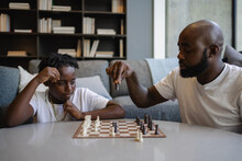 Black Father And Son Playing Chess In Living Room
