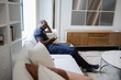 © Creative Flame - Black Man sitting on sofa and using smart phone